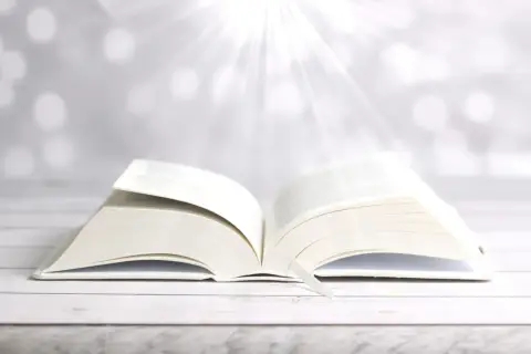 Ein aufgeschlagenes Buch mit einem Lesezeichen, das Lichtstrahlen empfängt. Wie in Phlm 1:3, ein Symbol für Hoffnung und Weisheit.
