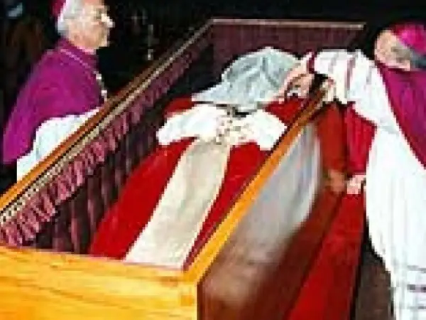 Würdenträger bei der Umbettung von Johannes Paul II. im Sarg, der mit rotem Stoff und weißen Bändern geschmückt ist.